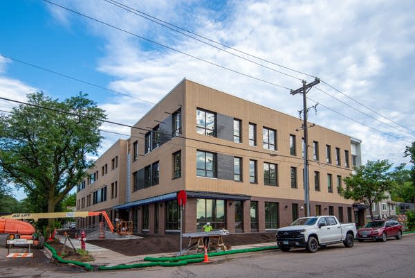 Construction equipment next to a three-story building on a corner