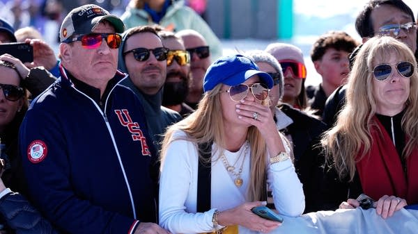 Spectators at the finish react after a downhill skier crashed
