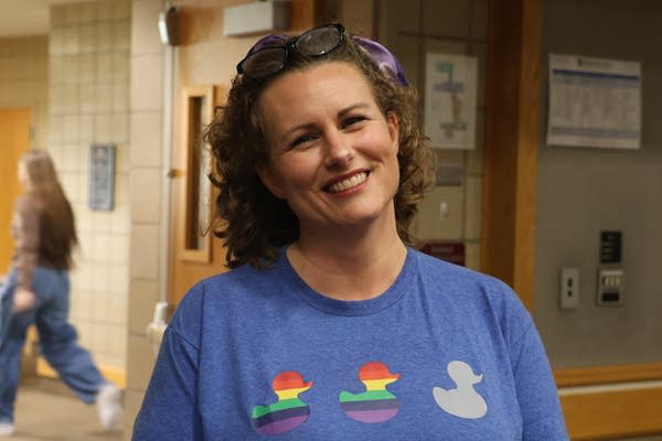 A woman smiles for a photo in a school hallway.