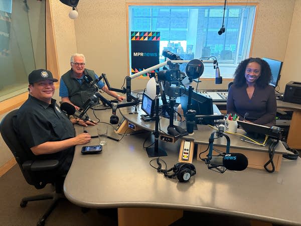 three people smiling in a broadcast studio