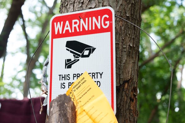 A sign warning of video surveillance is pinned to a tree.
